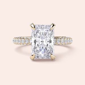 Radiant-cut diamond engagement ring with side stone accents in 14K yellow gold, displayed on a neutral background.