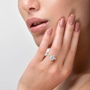 Close-up of a woman wearing a stunning oval diamond engagement ring in 14K or 18K gold with a split shank and hidden halo.