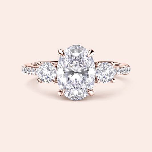Oval diamond engagement ring in 14K rose gold, featuring a central oval diamond with side round stones and pave accents.