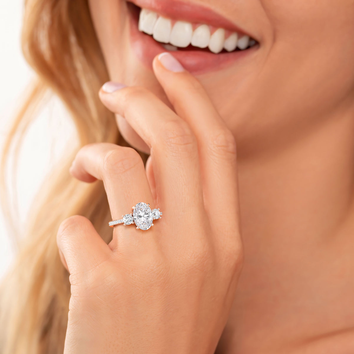 "Woman wearing a stunning 14K or 18K rose gold engagement ring with a large oval diamond and pave accent stones."