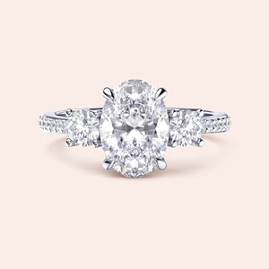 Elegant three-stone engagement ring in 14K/18K gold or platinum, featuring an oval diamond and sparkling side stones.
