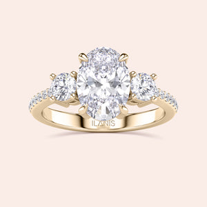 Three-stone oval engagement ring with diamond center stone in 14K or 18K gold, featuring pave side stones for added sparkle.