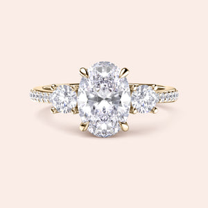 Elegant three-stone engagement ring with oval-cut diamond and round-cut stones in 14K yellow gold or platinum, featuring aPave band.