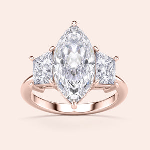Rose gold engagement ring featuring a marquise-cut diamond and two princess-cut diamonds, available in 14K, 18K, or platinum.