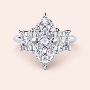 Elegant platinum three-stone engagement ring featuring a marquise-cut diamond and princess-cut side diamonds.