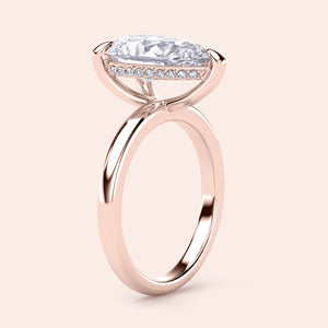 Elegant 14K rose gold engagement ring featuring a pear-shaped diamond with a hidden halo and a simple band design. 
