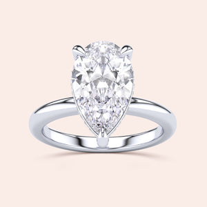 Elegant 14K or 18K white gold pear-shaped diamond engagement ring with a hidden halo and polished band, sparkling centerpiece. 