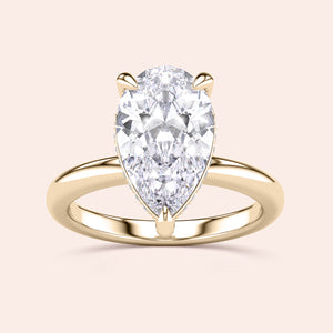 Elegant pear-shaped diamond ring in 14K or 18K yellow gold, featuring a hidden halo and plain band, radiating timeless beauty. 