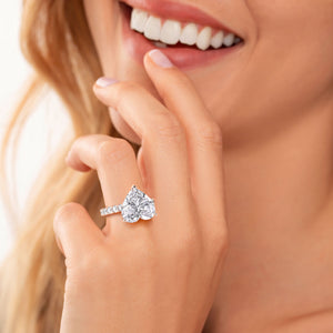 Woman wearing a heart-shaped diamond ring with hidden halo in 14K/18K rose gold, featuring sparkling accents.