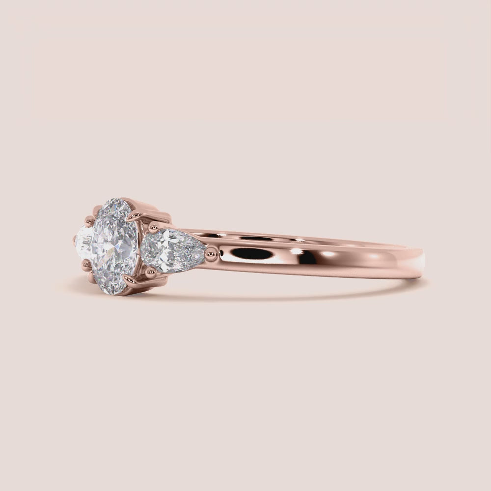 "Rose Gold 14K engagement ring featuring a small oval cut and three side pear stones, perfect for your unique love story.|







#14KRecycledRoseGold
#18KRecycledRoseGold


"
