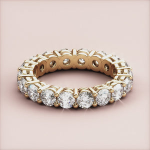 Elegant yellow gold eternity wedding band featuring round brilliant diamonds in a 360-degree prong setting, available in 14K or 18K. 