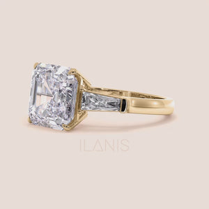 Elegant yellow gold engagement ring featuring a radiant cut center diamond with two side baguettes on a smooth band 