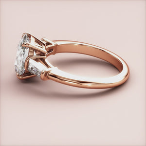 14K rose gold engagement ring with an oval diamond and tapered baguette side stones on a model's finger.