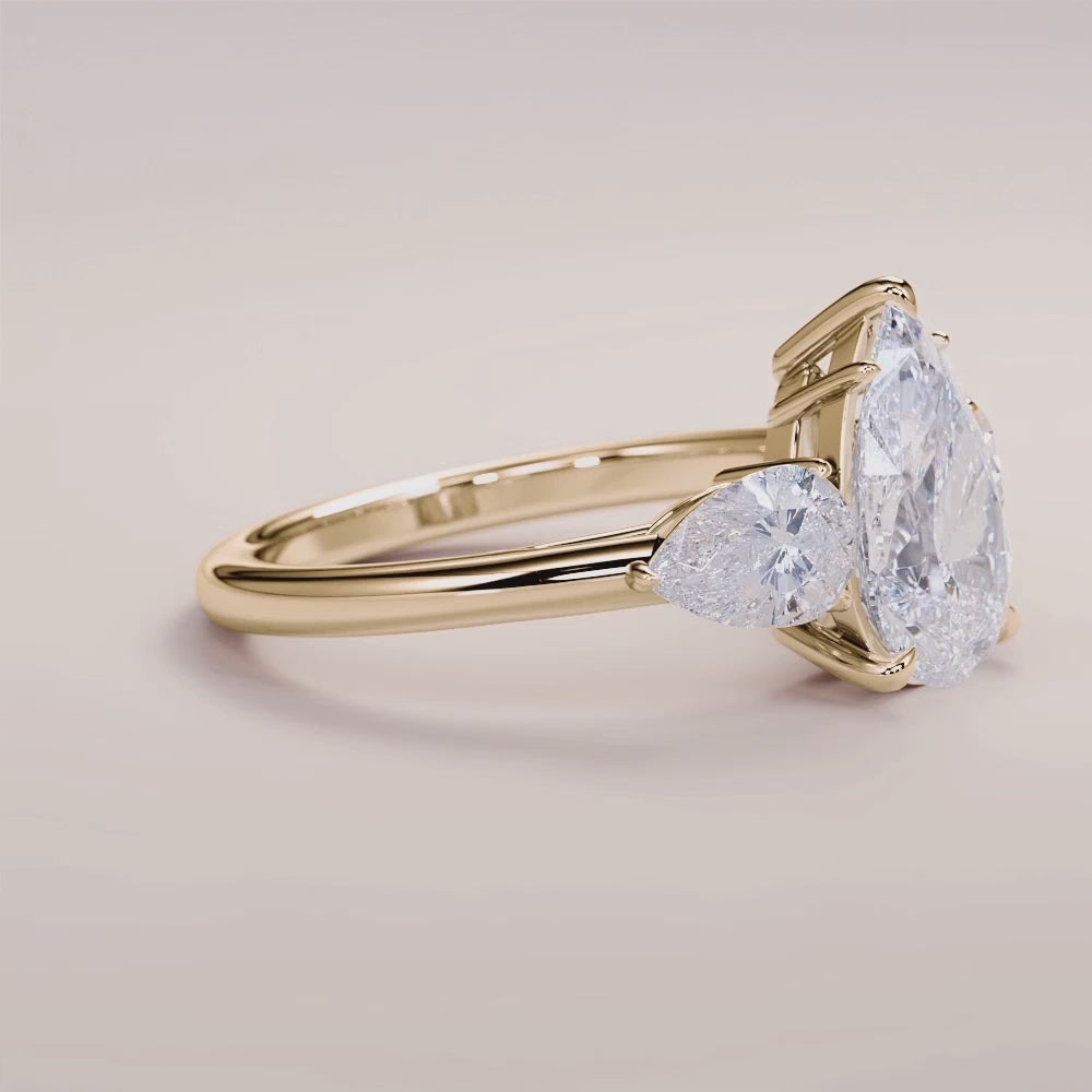 Elegant three-stone engagement ring in 14K or 18K yellow gold, featuring an oval diamond with pear side stones.|




#14KRecycledYellowGold
#18KRecycledYellowGold





