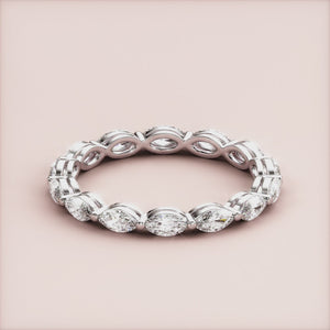 Elegant 14K/18K gold or platinum wedding band featuring marquise-cut diamonds in an eternity style, set against a neutral beige background. 
