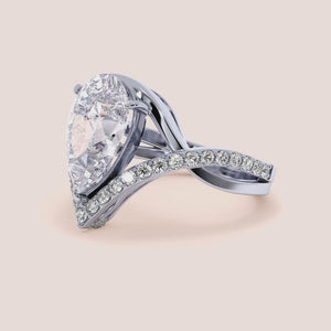 Stunning 14K, 18K, or platinum ring with a pear-shaped diamond and smaller accent diamonds for added brilliance.