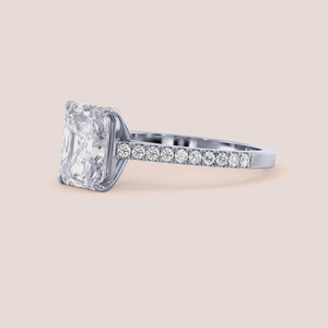 Radiant cut diamond ring with pavé band in customizable 14K, 18K gold, or platinum, perfect for elegant occasions.
