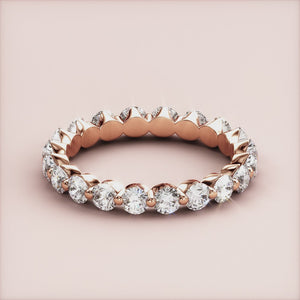 Elegant 14K Rose Gold eternity band featuring round brilliant cut diamonds in prong setting, perfect for weddings or engagements. 