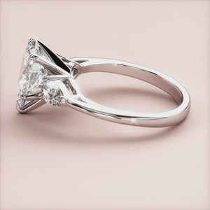 Elegant 14K and 18K gold engagement ring with a pear-shaped diamond centerpiece and two smaller diamonds on a sleek band.