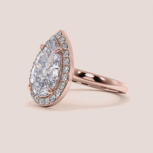 Rose gold teardrop halo engagement ring set featuring pear-shaped diamond, with options in 14K, 18K, or platinum settings.