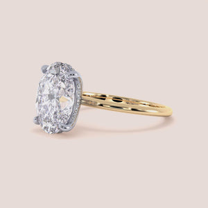 Two-tone 14K white and yellow gold oval-cut diamond solitaire ring, perfect for engagement or wedding, shown on a model's hand. 