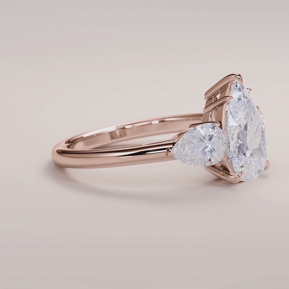 "Rose Gold 14K engagement ring featuring a pear three-stone design with side stones, perfect for timeless elegance.|







#14KRecycledRoseGold
#18KRecycledRoseGold


"
