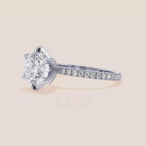 Close-up video of white gold or platinum round diamond engagement ring with pavé band, capturing brilliance, light performance and accent diamond prongs in motion 