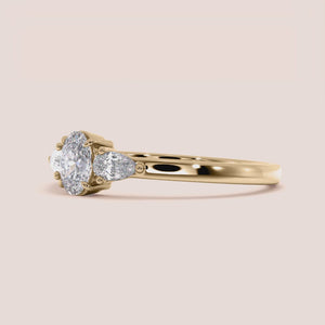 """Stunning 14K Yellow Gold three-stone engagement ring with oval center and pear side stones, perfect for a romantic proposal.""