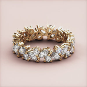 Intricate yellow gold eternity ring featuring marquise and pear diamonds; available in 14K, 18K, or platinum wedding band options. 