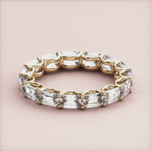 Luxurious emerald-cut diamond eternity band in 14K or 18K yellow gold, perfect for weddings and special occasions. 