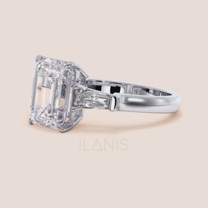 White gold engagement ring featuring a prominent emerald-cut diamond, flanked by smaller diamonds on a delicate band, exuding luxury. 