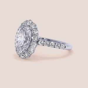 Elegant oval-shaped diamond halo ring in 14K or 18K gold or platinum, featuring sparkling accent stones around the central diamond.
