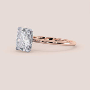 Two-tone 14K/18K white and rose gold diamond solitaire ring featuring a cushion-cut design and secret halo. 