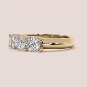 Elegant three-stone wedding band in 14K or 18K gold or platinum, featuring a round cut diamond design. 