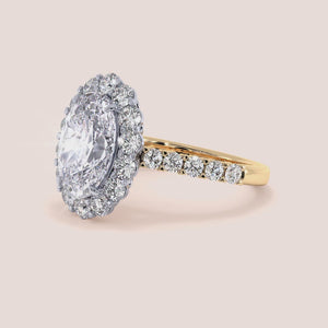 Two-tone 18K oval diamond engagement ring with halo and pave band in yellow and white gold, showcasing exquisite craftsmanship. 