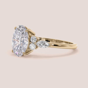 Gold engagement ring with oval-shaped diamond and marquise accents, available in 14K, 18K, or platinum for stunning elegance.
