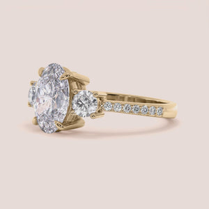 "Elegant 14K yellow gold Reese oval engagement ring with three stunning side stones and pave detailing, perfect for romantic proposals.