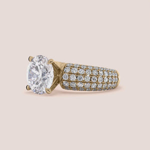 Luxurious round diamond ring in 14K or 18K gold or platinum, featuring an oval-cut diamond solitaire and smaller diamonds on the band.

