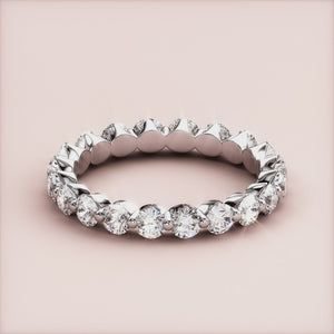 14K or 18K white gold eternity wedding band with round brilliant-cut diamonds, elegantly displayed on a beige background. 