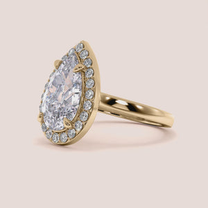 Elegant pear-shaped diamond engagement ring set in 14K or 18K gold, featuring a brilliant halo of smaller diamonds.