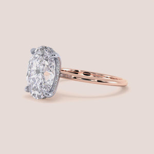 Two-tone 14K/18K white and rose gold engagement ring featuring an oval cut diamond in a secret halo solitaire design. 