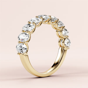 Elegant 14K or 18K yellow gold oval half eternity wedding band with round brilliant cut diamonds on a soft pink background. 