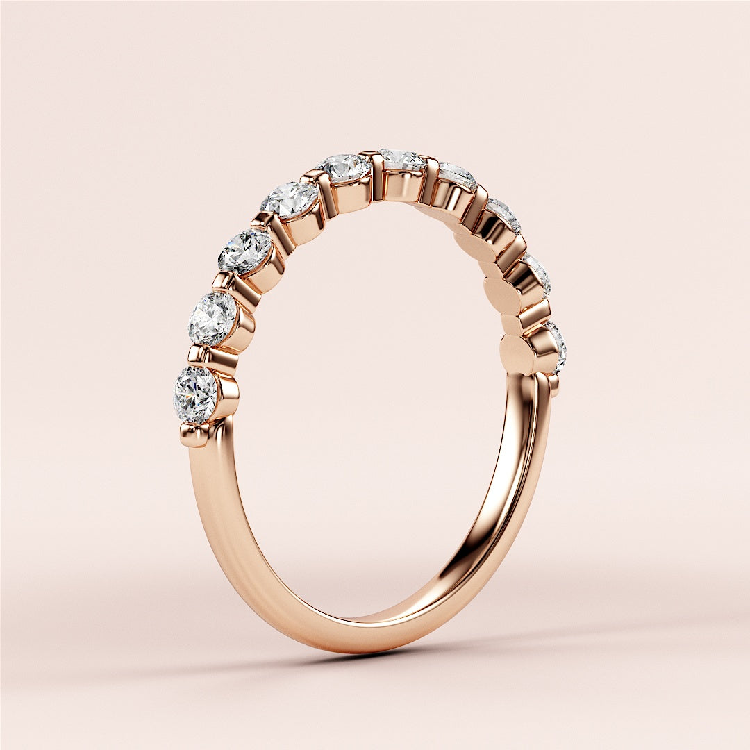 Elegant 14K rose gold half eternity wedding band with shared prong setting and dazzling round brilliant-cut diamonds. 