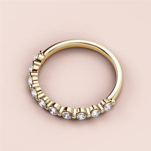 Elegant 14K Gold wedding band featuring round brilliant diamonds, showcasing half eternity shared prong design on a neutral background. 