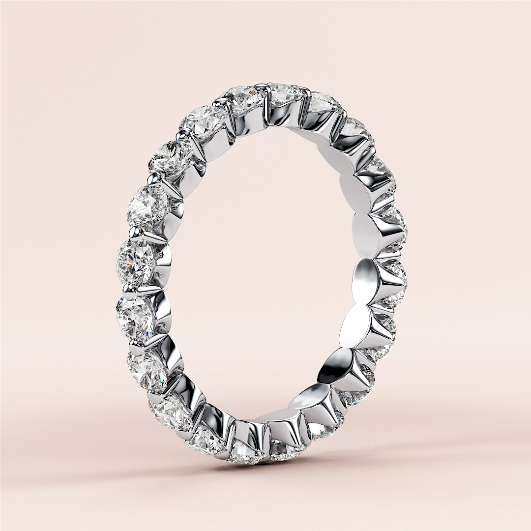 14K or 18K white gold eternity wedding band with round brilliant-cut diamonds, elegantly displayed on a beige background. 