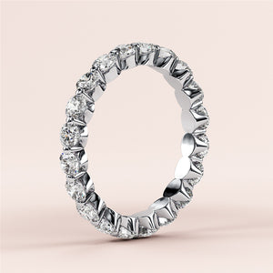 14K or 18K white gold eternity wedding band with round brilliant-cut diamonds, elegantly displayed on a beige background. 