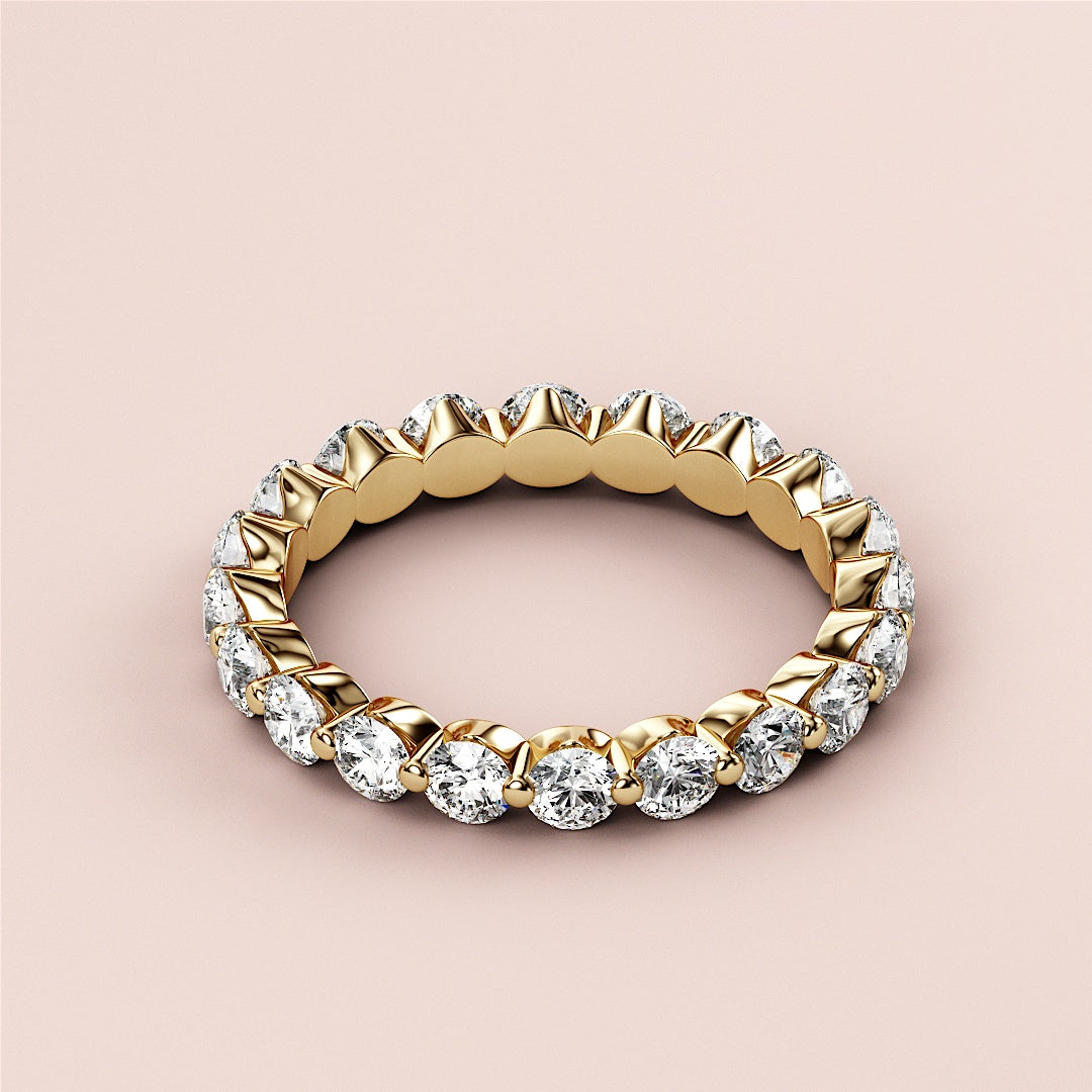 Elegant 14K/18K gold marquise diamond eternity wedding band with clear marquise diamonds, displayed on a soft beige background. 