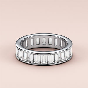Elegant emerald channel eternity ring in 14K or 18K white gold, featuring baguette-cut diamonds, perfect for weddings. 