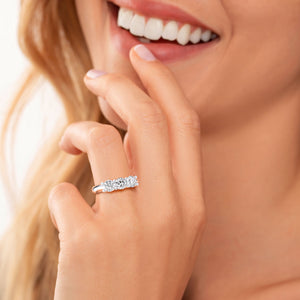 Elegant 14K or 18K gold round three-stone U-prong wedding band worn on a model's finger. Perfect for eternity jewelry lovers. 
