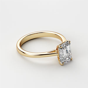 Elegant emerald-cut solitaire engagement ring in 14K or 18K yellow gold, highlighting the diamond's timeless beauty and sparkle.